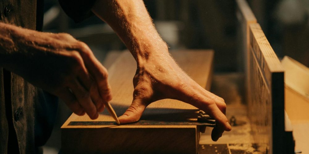 A craftsman skillfully sanding a wooden plank in a well-lit workshop.